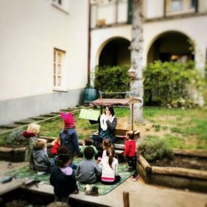 Maestra narra a bimbi nel cortile della scuola