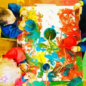 Bimbi del nido pitturano insieme su un grande foglio