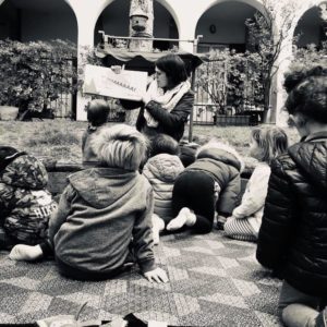 Bimbi in cortile ascoltano maestra che legge un racconto