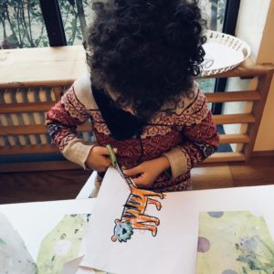 Bimba ritaglia il disegno di una tigre con le forbici