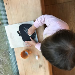 Bimba disegna con il gesso su una lavagnetta