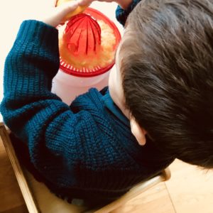 Bimbo spreme un'arancia con uno spremiagrumi