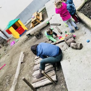 Maestra e bimbi costruiscono un percorso nel cortile della scuola