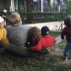 Bimbi e maestra con chitarra sull'amaca in cortile