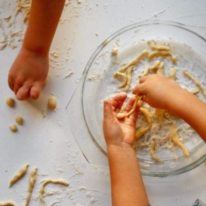 Mani di bimbi che preparano pasta fresca