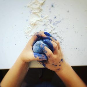 Mani di bimbo che manipola pasta colorata