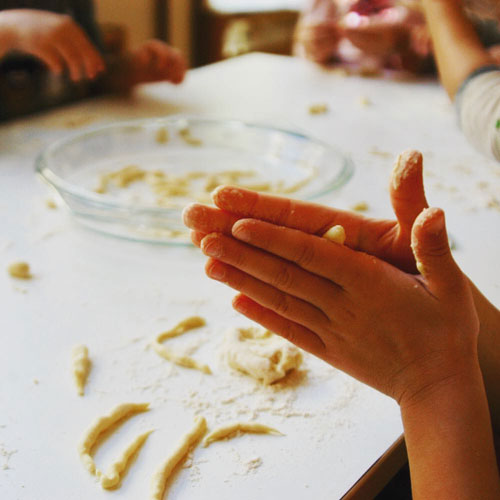 Mani di bimba che fanno la pasta fresca