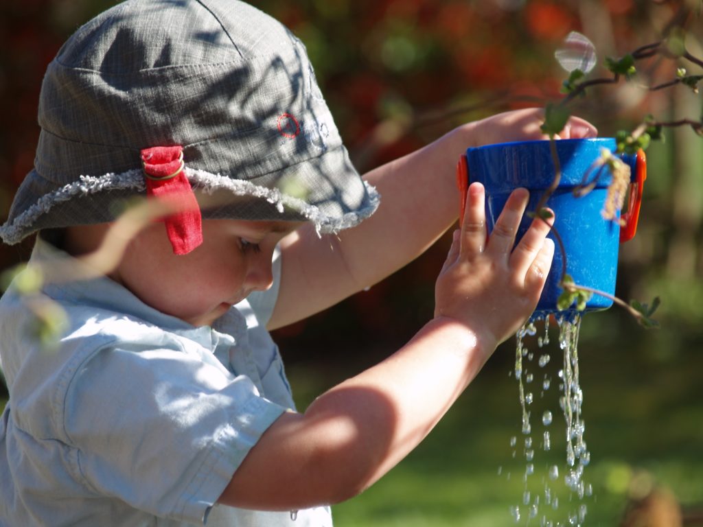 Bambino che gioca con secchiello pieno d'acqua